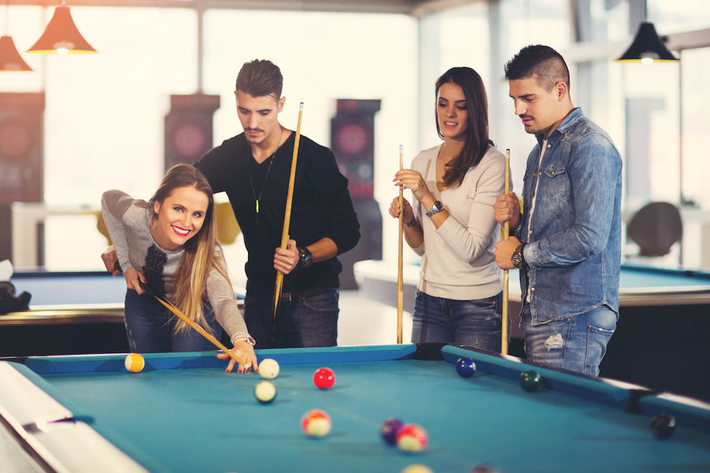 Two young men and two young women playing a game of pool